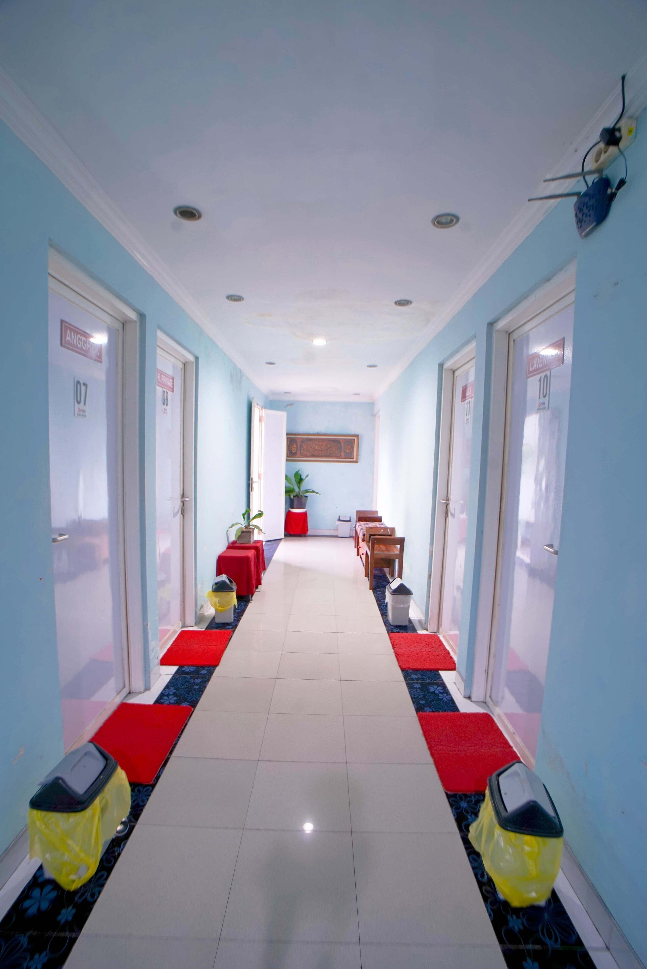 A hotel hallway with doors labeled 107 and 108, a red carpet, and a potted plant in the center.