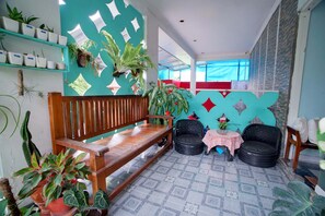A room with a wooden bench, a small table with a tablecloth, and various potted plants. - Zaira Residence By Occupied (Ngaglik)