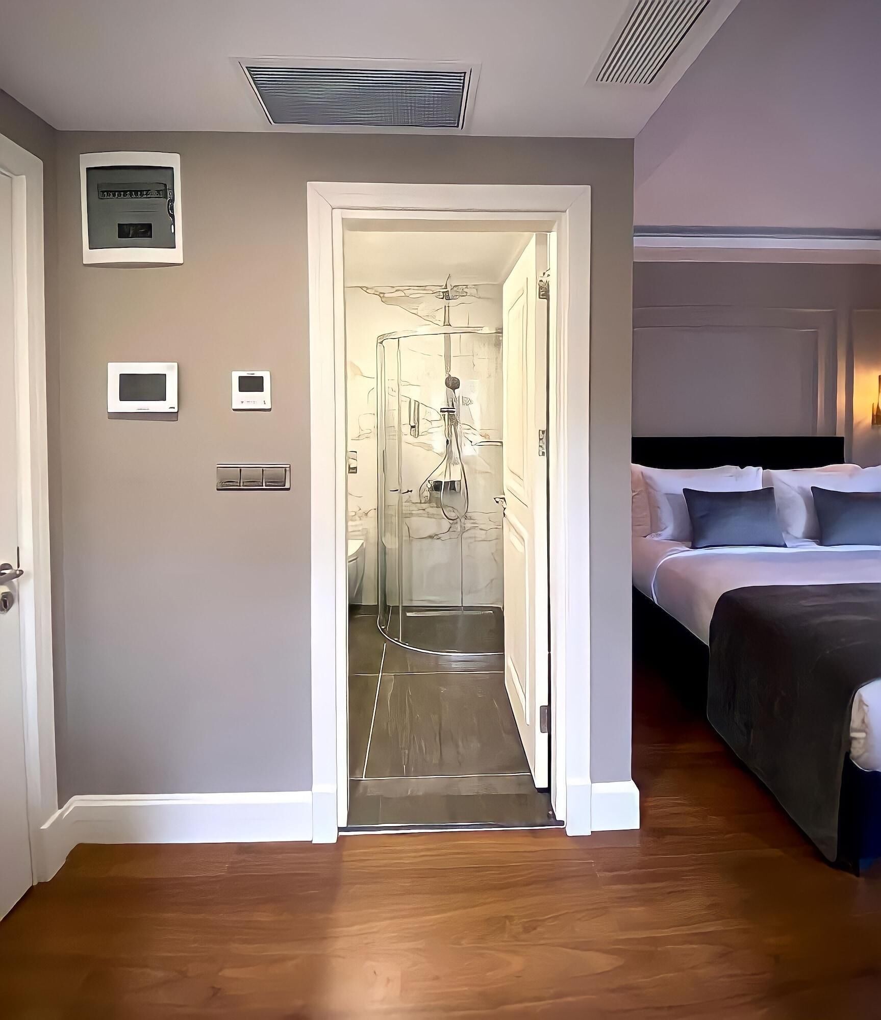 Quarto de hotel com uma cama, chuveiro e porta para o banheiro.