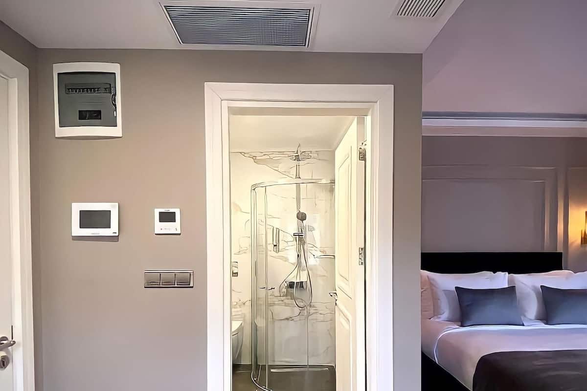 Quarto de hotel com uma cama, chuveiro e porta para o banheiro.