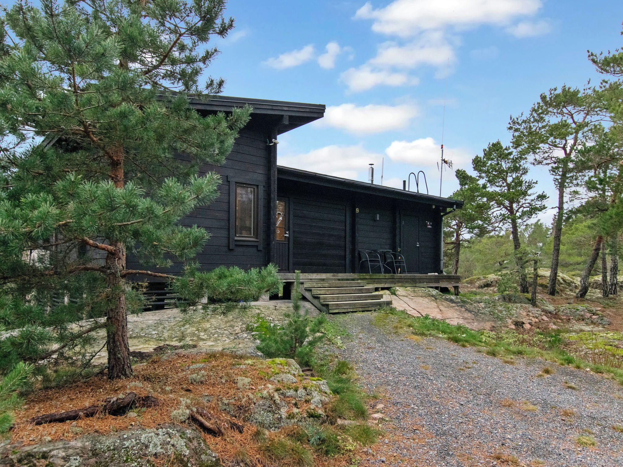 Une cabane avec une façade en bois, une véranda et une allée gravillonnée.