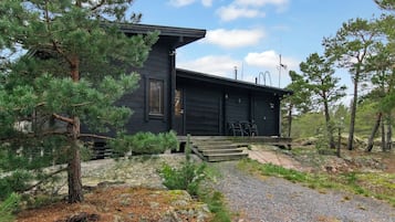 Eine Holzhütte mit Veranda und Auffahrt mit Schotter.