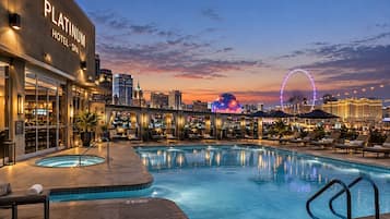 A hotel with a swimming pool, lounge area, and city skyline views.