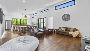 A spacious living area with a dining table, sofas, and a large rug. - Sandy Feet Retreat Inverloch (Inverloch)
