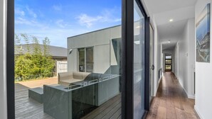A modern house with a covered outdoor seating area, a large sliding glass door, and a view of the backyard. - Sandy Feet Retreat Inverloch (Inverloch)