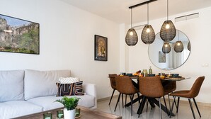 Ein modernes Wohnzimmer mit Sofa, Couchtisch und Essbereich mit Stühlen und einem Tisch für zwei Personen.