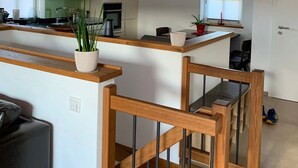 Une cuisine spacieuse avec des poutres apparentes, un coin repas agrémenté d’un escalier en bois, et une vue sur l’extérieur.