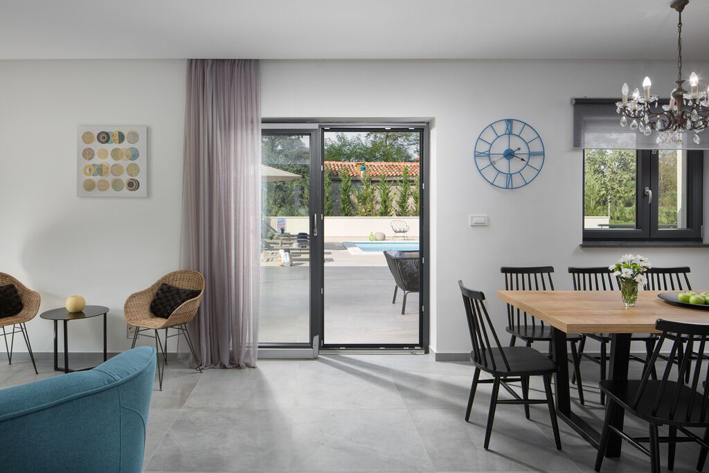 Ein modernes Wohnzimmer mit Essbereich, einem großen Fenster und Blick auf einen Außenpool.