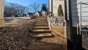 A residential driveway with a stone pathway leading to a wooden staircase. - Colony Suite - Bridgegate (Marietta)