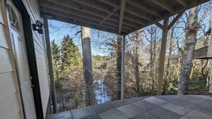 A covered porch with a view of a wooded area and a body of water. - Colony Suite - Bridgegate (Marietta)