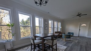 A spacious room with a dining table and chairs, large windows, a ceiling fan, and a door. - Colony Suite - Bridgegate (Marietta)