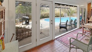 A covered patio with a pool, outdoor furniture, and a grill area. - Poolside Paradise - Historic District Home (College Station)
