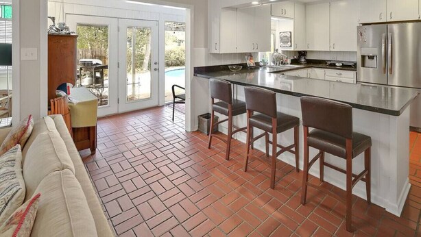 A modern kitchen with a central island, white cabinets, and stainless steel appliances. - Poolside Paradise - Historic District Home (College Station)