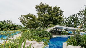 A swimming pool surrounded by lush greenery and a covered seating area. - Cozy Seaside Studio with Balcony Scenic Ocean View (Lapu-Lapy City)