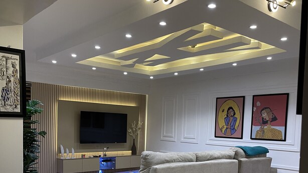 A modern living room with a large sofa, a flat-screen TV, and decorative wall art.