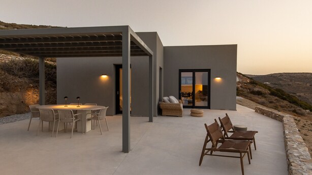 Eine moderne Außenpatio mit Esstisch und Stühlen, einer überdachten Sitzgruppe und Blick auf die umliegende Landschaft.