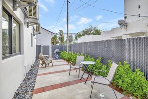Eine Terrasse mit Gartenmöbeln, einem Grill und einem Zierzaun.