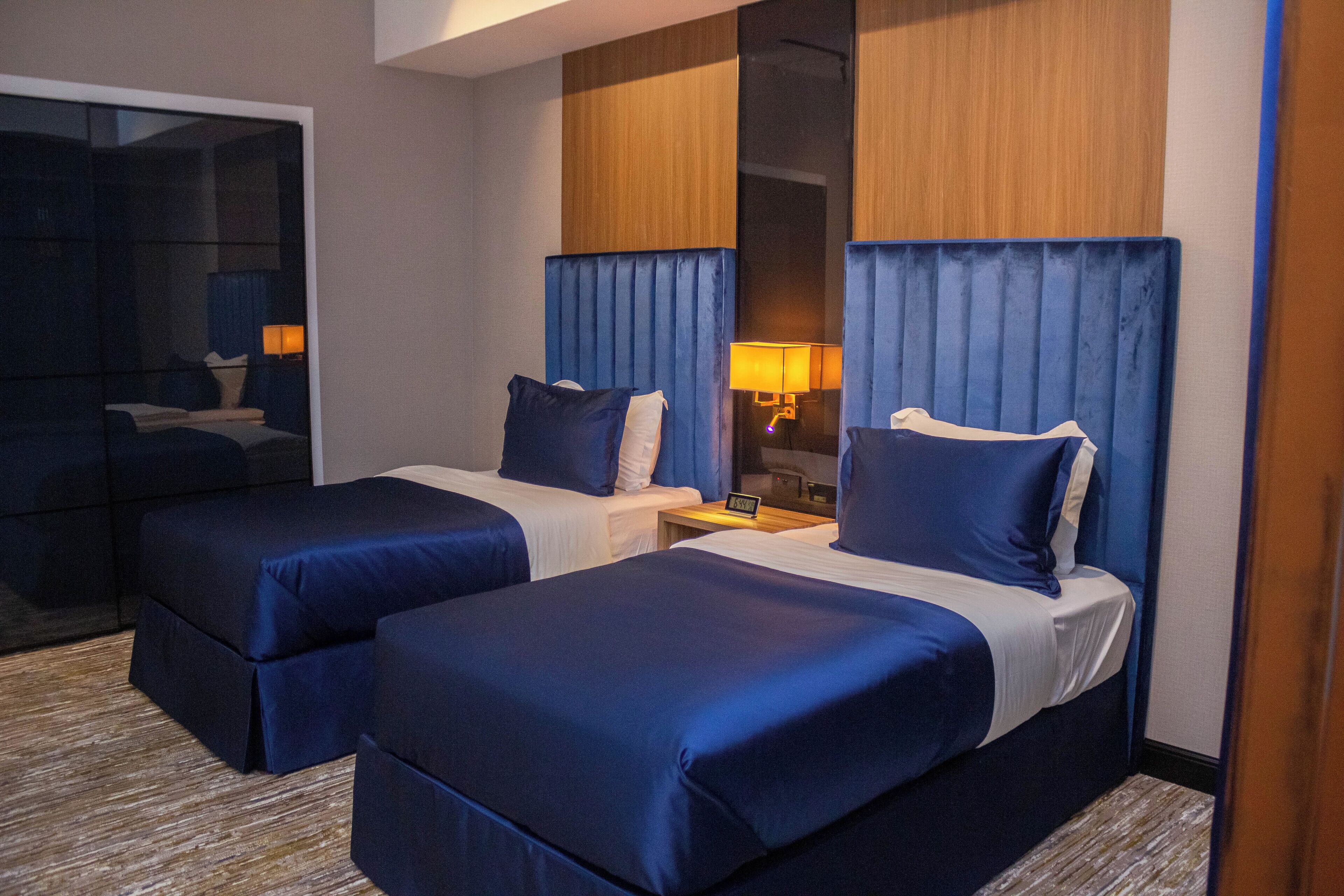 A hotel room with two beds, a nightstand, and a mirror.
