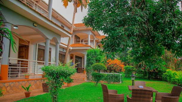 A courtyard with a dining area, potted plants, and a staircase leading to an upper level. - Calm Suites Kampala (Kampala)