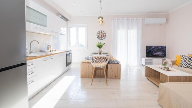A modern kitchen with white cabinets, a wooden dining table, and a built-in oven.