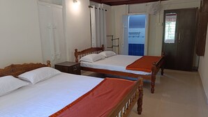 Una habitación con dos camas de madera, una mesita de noche pequeña, un armario y una puerta que da a un balcón.