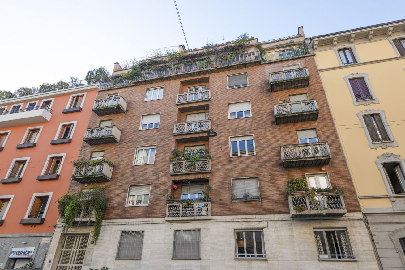 A multi-story building with balconies, windows, and a visible storefront.