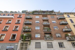 A multi-story building with balconies, a visible shop sign, and a clear view of the street.