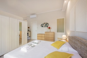 Una habitación de hotel con cama, armario, tocador, espejo y un adorno en la pared.