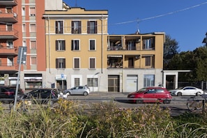 A multi-story building with balconies, a parking sign, and several parked cars. - BnButler - Maloja, 10 (Milano)