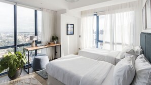 A modern hotel room with two beds, a desk, a potted plant, and a city view. - Elegant One-Bedroom Haven with Multiple Views at Cebu IT Park (Cebu City)