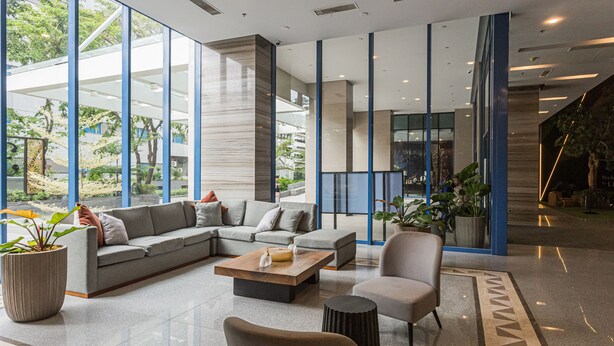 A modern lobby with a sectional sofa, a coffee table, and a potted plant. - Elegant One-Bedroom Haven with Multiple Views at Cebu IT Park (Cebu City)