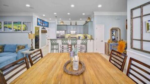 A dining area with a wooden table, chairs, and a decorative centerpiece. - Spacious 3bd/2ba Home in Destiny West-Beach Access-Pool-Hot Tub, Wi-Fi-Gym (Destin)