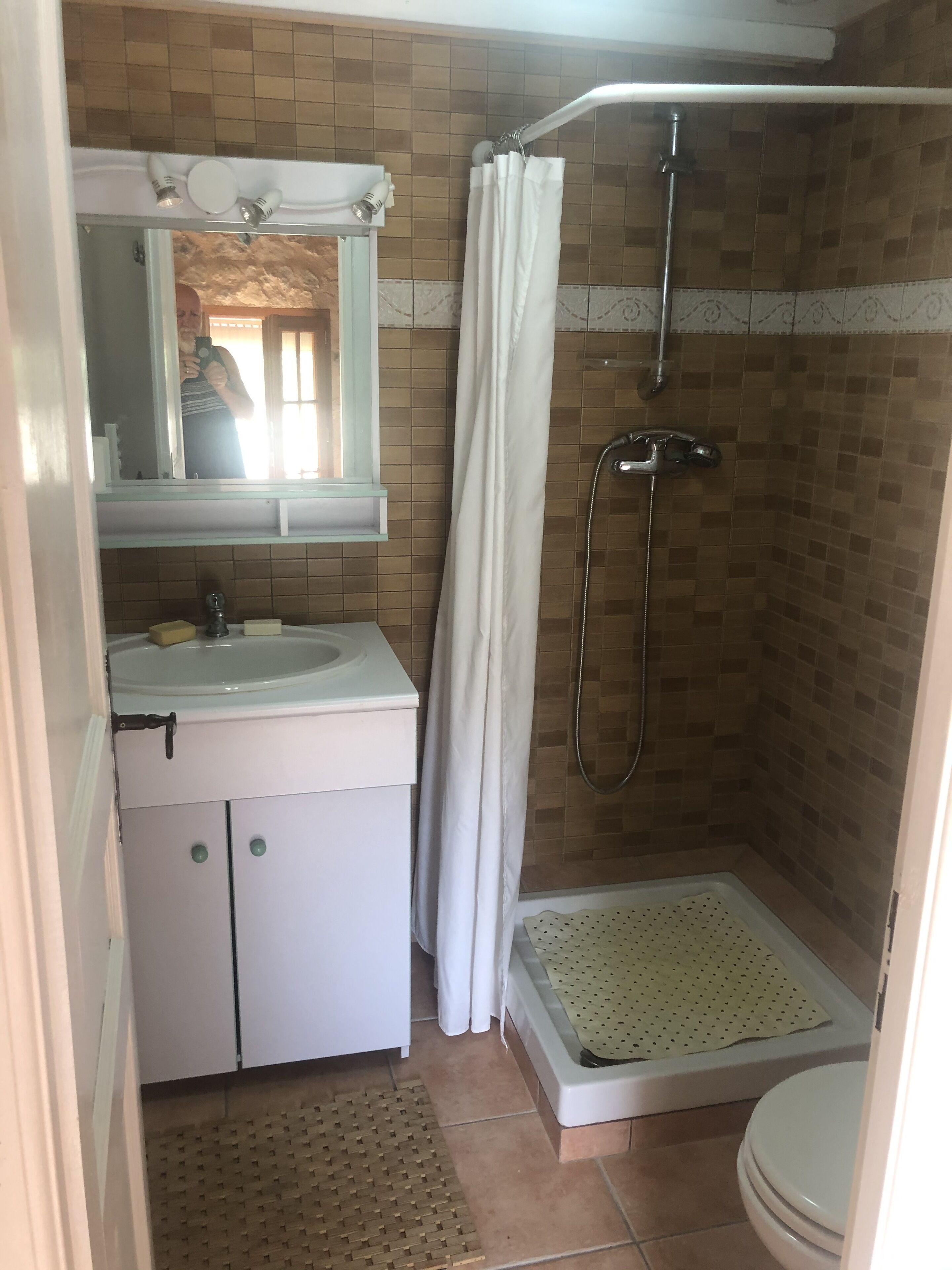 A bathroom with a shower, toilet, sink, and mirror.