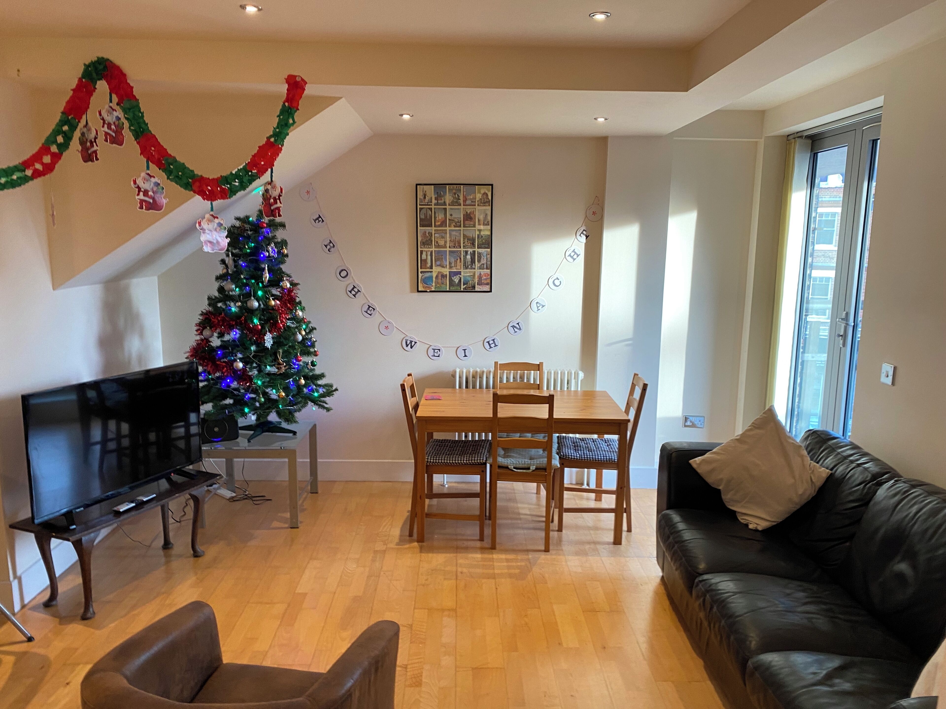 Een moderne woonkamer met een houten eettafel, een kerstboom en een leren bank.