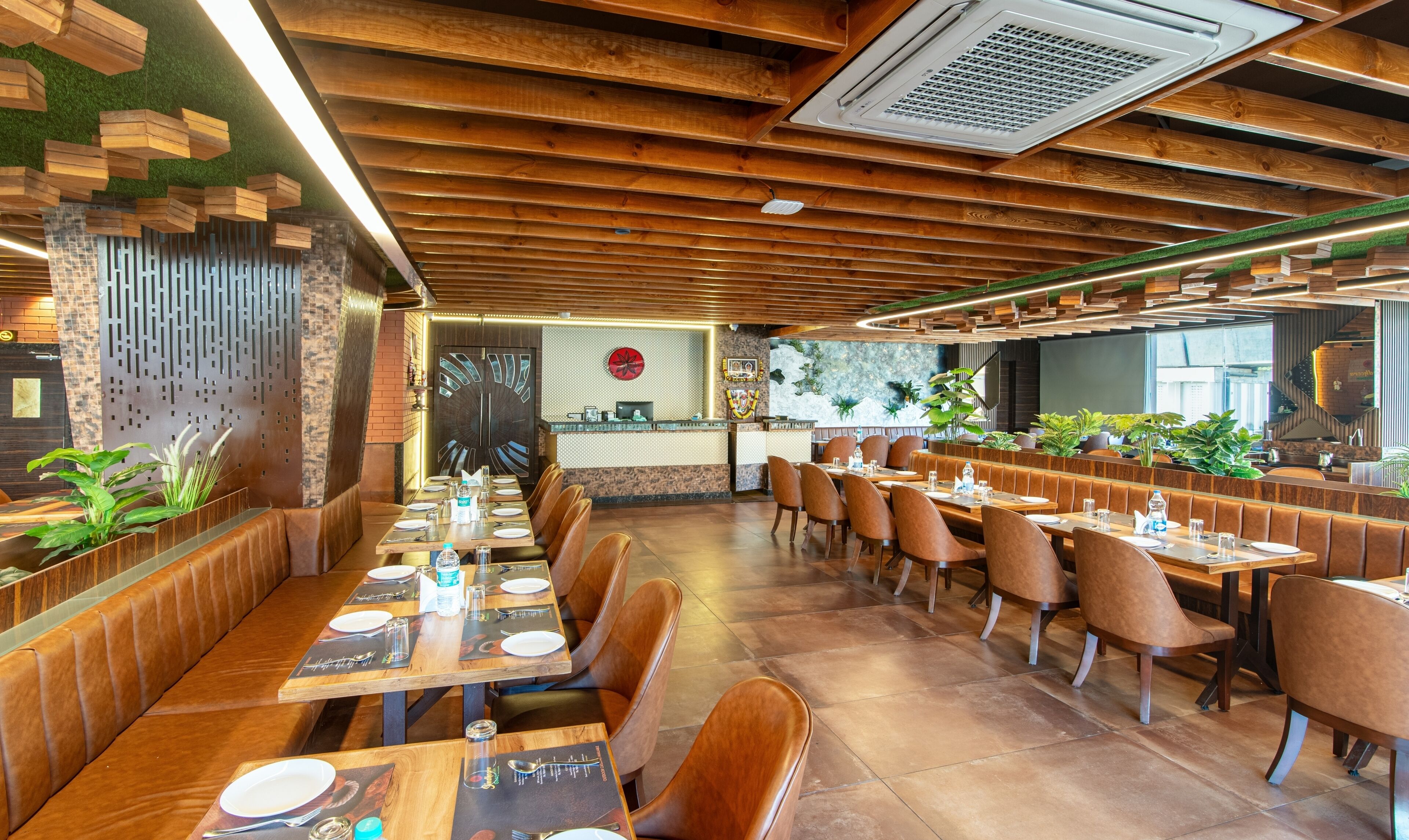 Un restaurante con vigas de madera en el techo, una recepción y cabinas con asientos de cuero marrón.