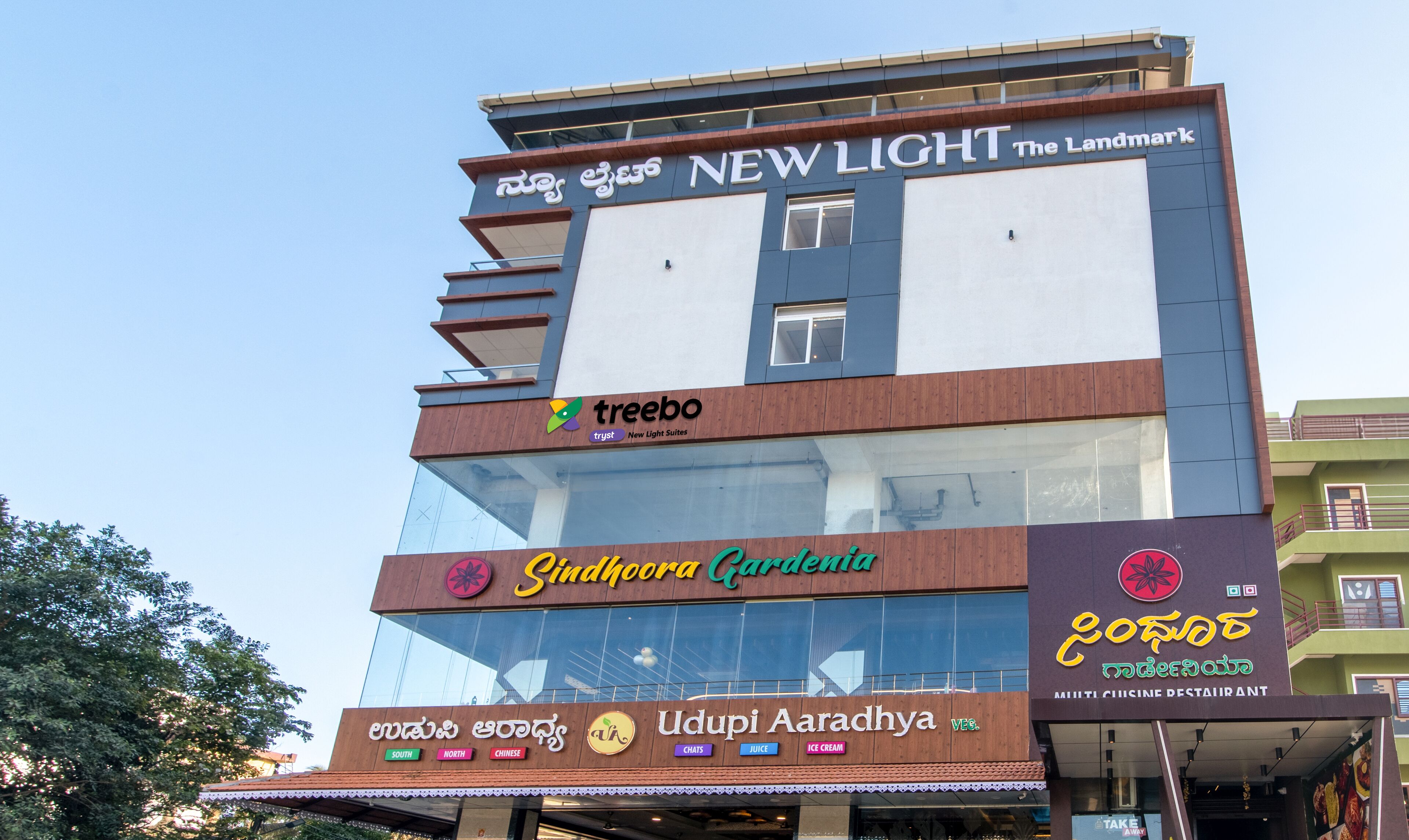 A multi-story building with various businesses including a hotel named 'New Light The Landmark', a restaurant 'Udupi Arachyya', and a cinema.