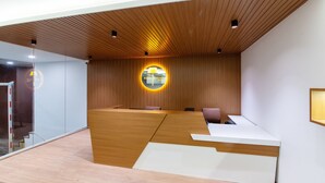 A modern reception area with a wooden reception desk, a glass wall, and a circular illuminated sign.