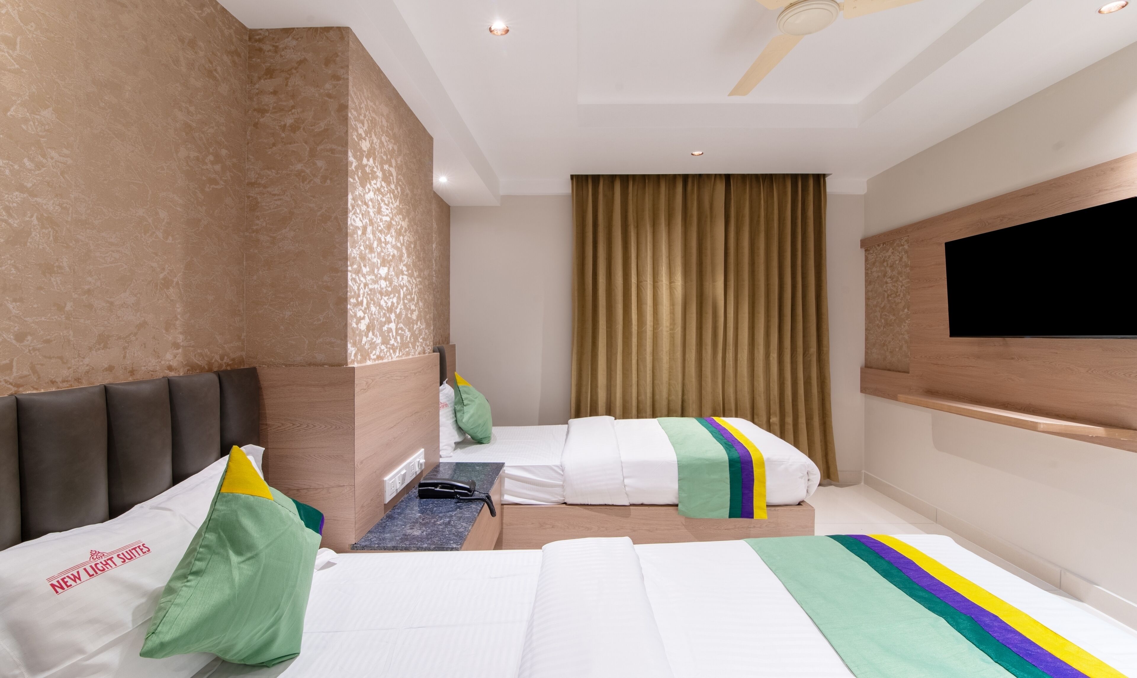 A hotel room with a bed, a desk, a chair, a television, and a window with curtains.