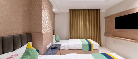 A hotel room with a bed, a desk, a chair, a television, and a window with curtains.