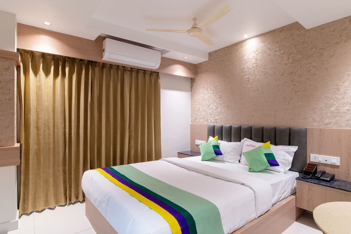 Una habitación de hotel con una cama, una mesita de noche, un escritorio y una silla.