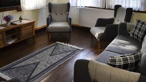 Un soggiorno con divano, poltrone, un tavolino in legno e televisore.
