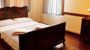 Un letto di legno con testiera, un comodino e una finestra con tende.