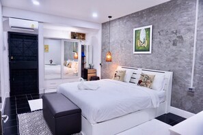 A modern bedroom with a large bed, a wardrobe, a bedside table, and a hanging light fixture. - P'Ja House (Hat Yai)