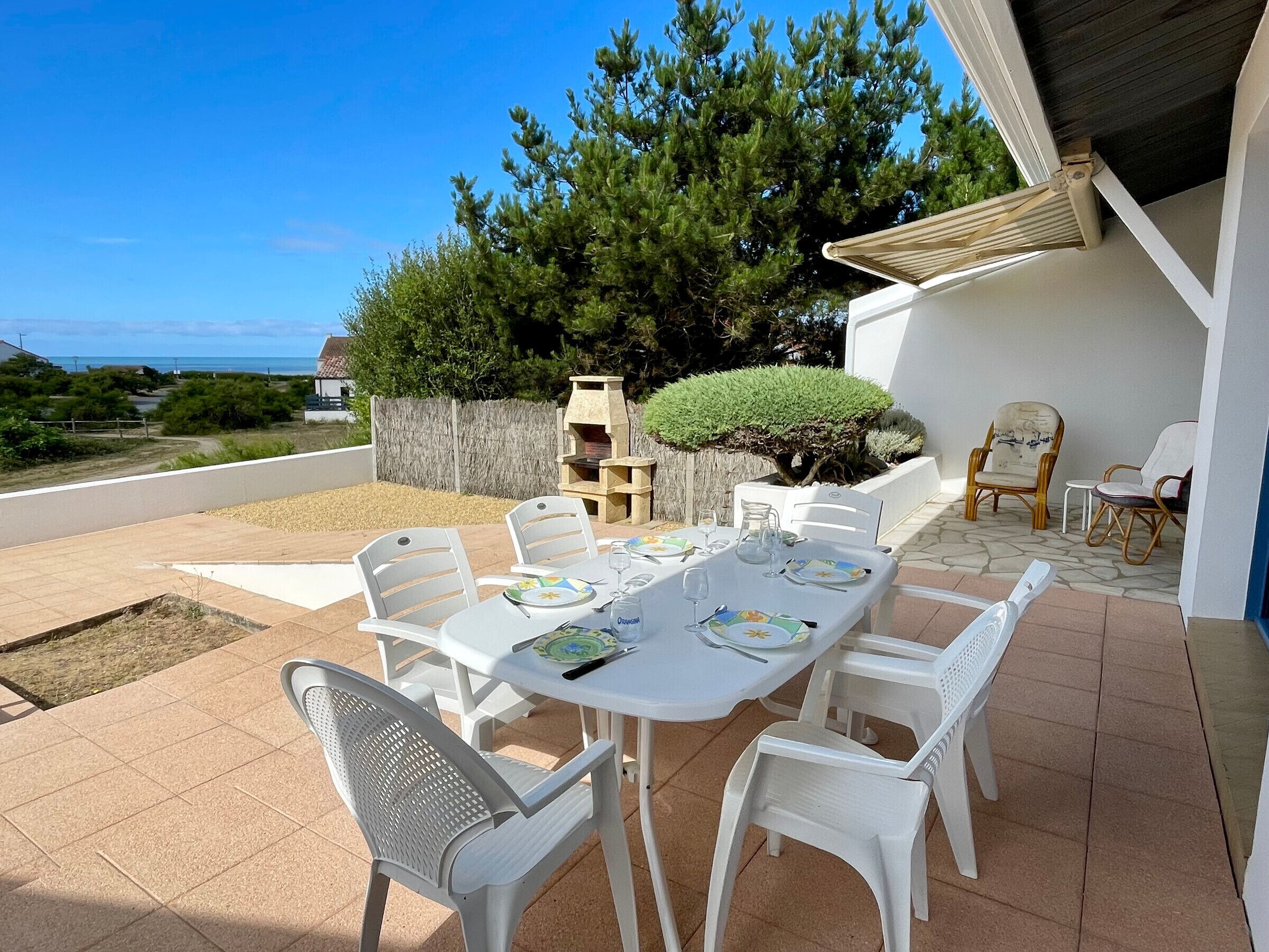 Eine Terrass mit Esstisch, umgeben von Stühlen und Blick auf das Meer.