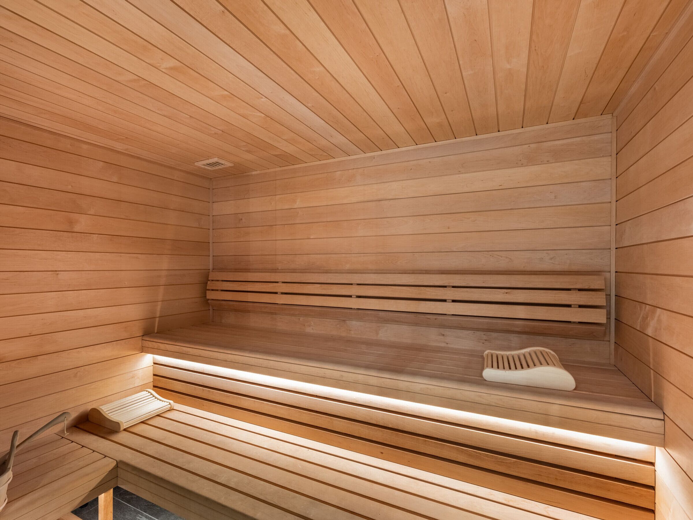 Un sauna avec des bancs en bois et un banc muni d’une serviette.