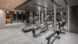 A modern gym with treadmills, elliptical machines, and a mirrored wall.