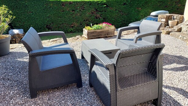 Mueble de mimbre exterior con vistas a un paisaje verde y colinas.