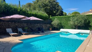 Una piscina con pared de piedra y sillas de descanso.