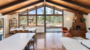 Una habitación amplia con techo alto, ventanas grandes, chimenea y zona de comedor.