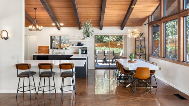 Una cocina amplia con una isla central, taburetes de bar y un comedor con una mesa grande y sillas.